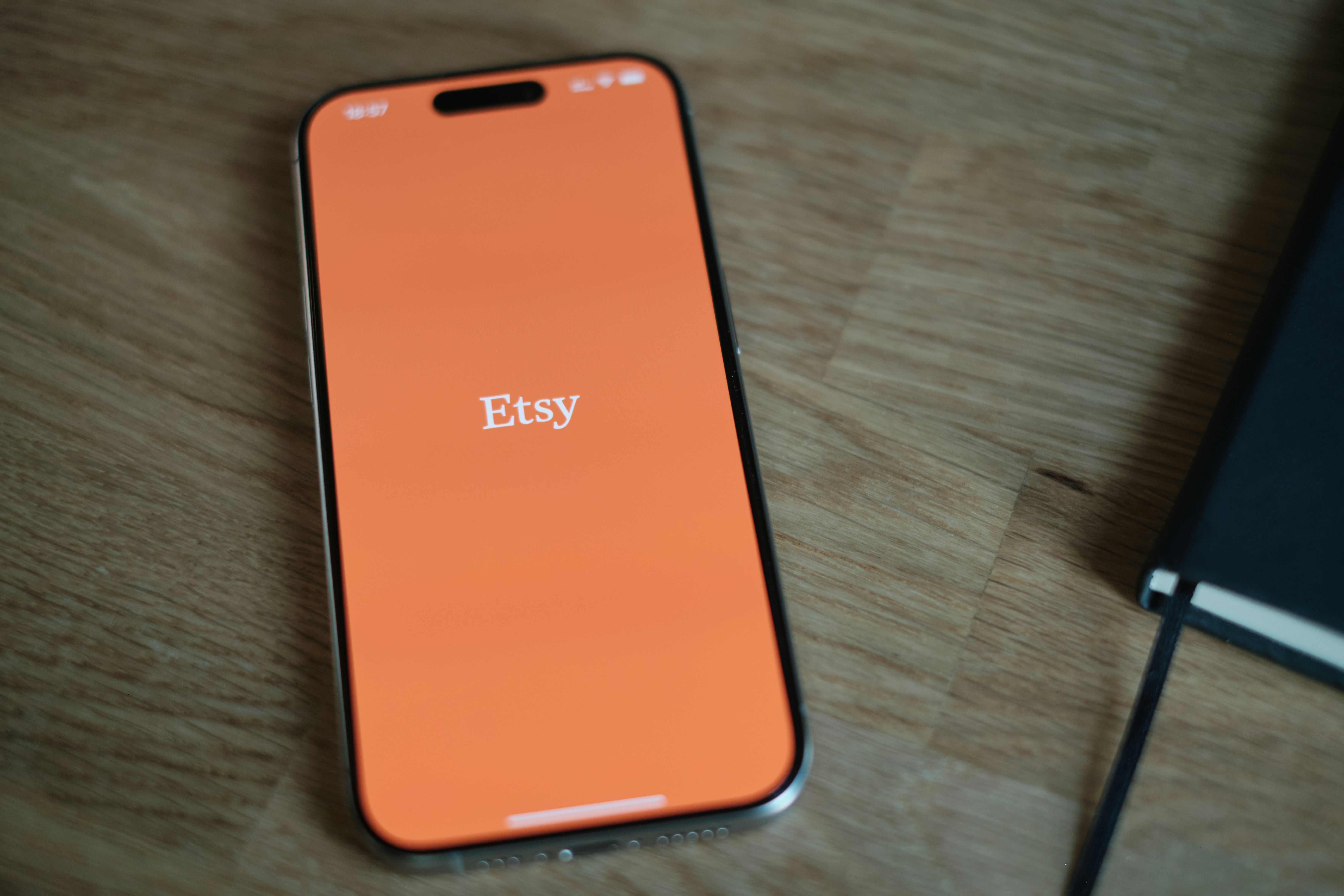 An orange cell phone sitting on top of a wooden table